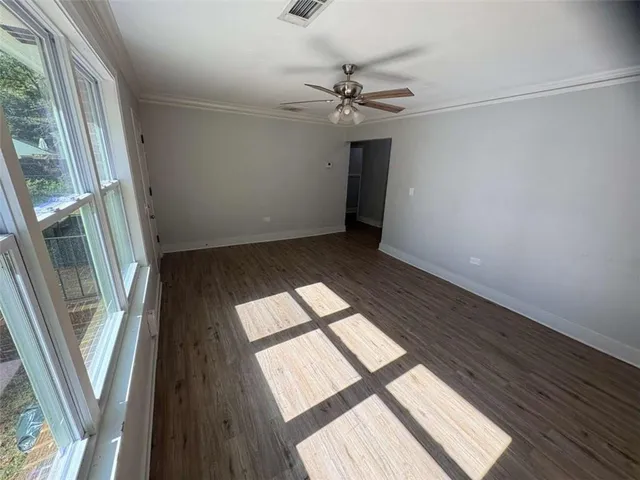 a view of an empty room and wooden floor and a kitchen view