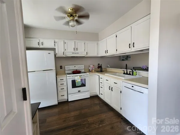 a kitchen with granite countertop white cabinets and white appliances
