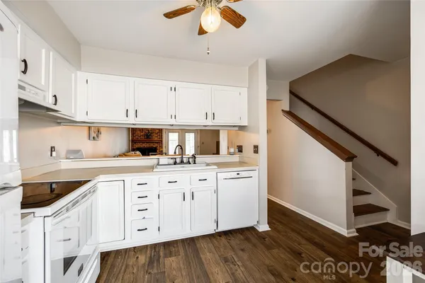 a kitchen with granite countertop white cabinets white appliances and sink