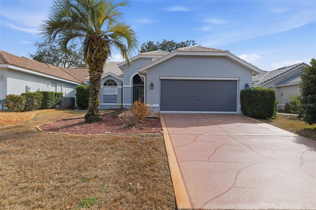 9376 French Quarters Circle Weeki Wachee, FL 34613 - Photo 2 of 43 a front view of a house with a yard and garage