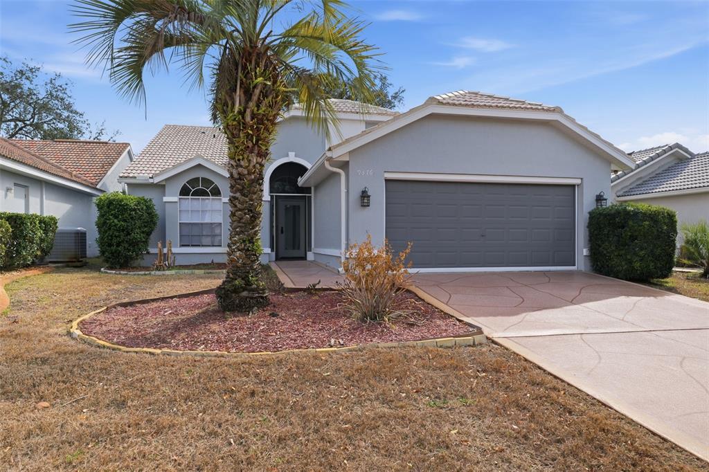 9376 French Quarters Circle Weeki Wachee, FL 34613 - Photo 37 of 43 a front view of a house with a yard and garage