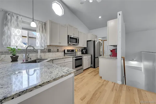 a kitchen with granite countertop a refrigerator a sink a stove a microwave and wooden cabinets