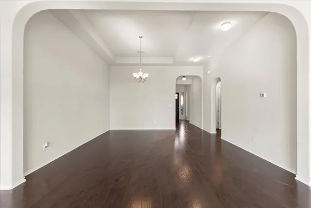 an empty room with wooden floor and a ceiling fan