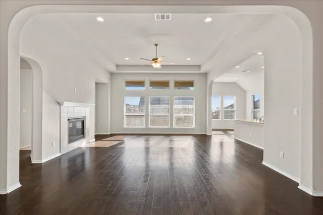 an empty room with wooden floor fireplace and windows