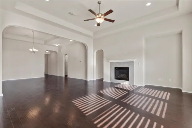 a view of a livingroom with a fireplace a ceiling fan and wooden floor