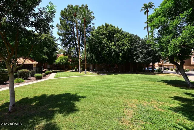 a front view of a building with garden and trees