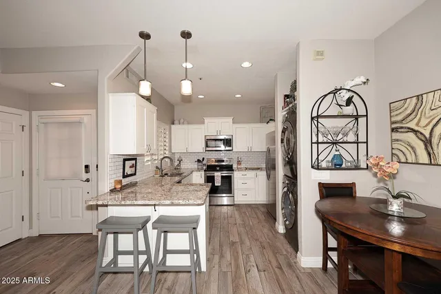 a kitchen with stainless steel appliances kitchen island granite countertop a table chairs and a refrigerator