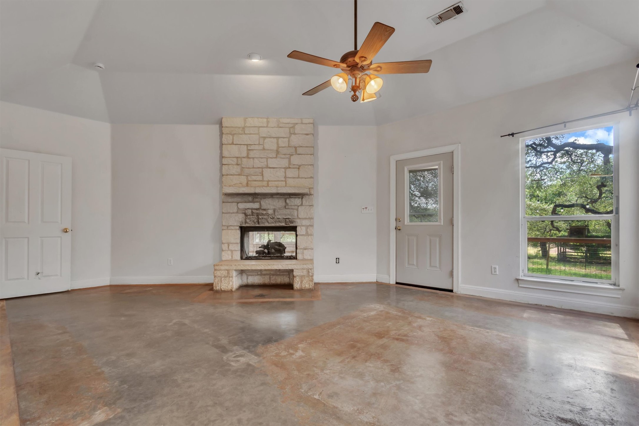 1120 Meadow Ridge Drive Austin, TX 78737 - Photo 16 of 40 A spacious room features a beautiful stone fireplace and ample natural light from a large window.