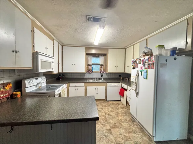 a kitchen with stainless steel appliances granite countertop a refrigerator a sink dishwasher and white cabinets with wooden floor