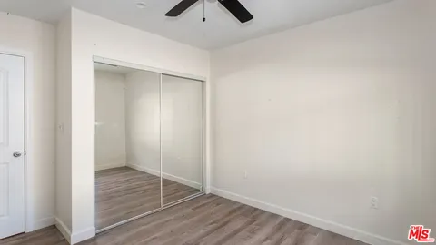 an empty room with closet and a ceiling fan
