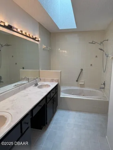 a spacious bathroom with a granite countertop sink a mirror and a bathtub