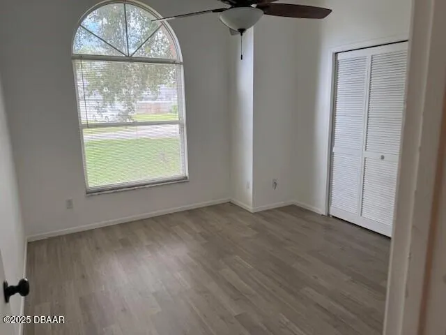 an empty room with wooden floor a chandelier and windows