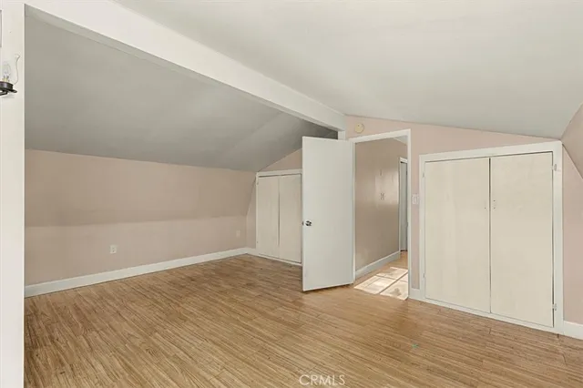 a view of an empty room with wooden floor fireplace and a window