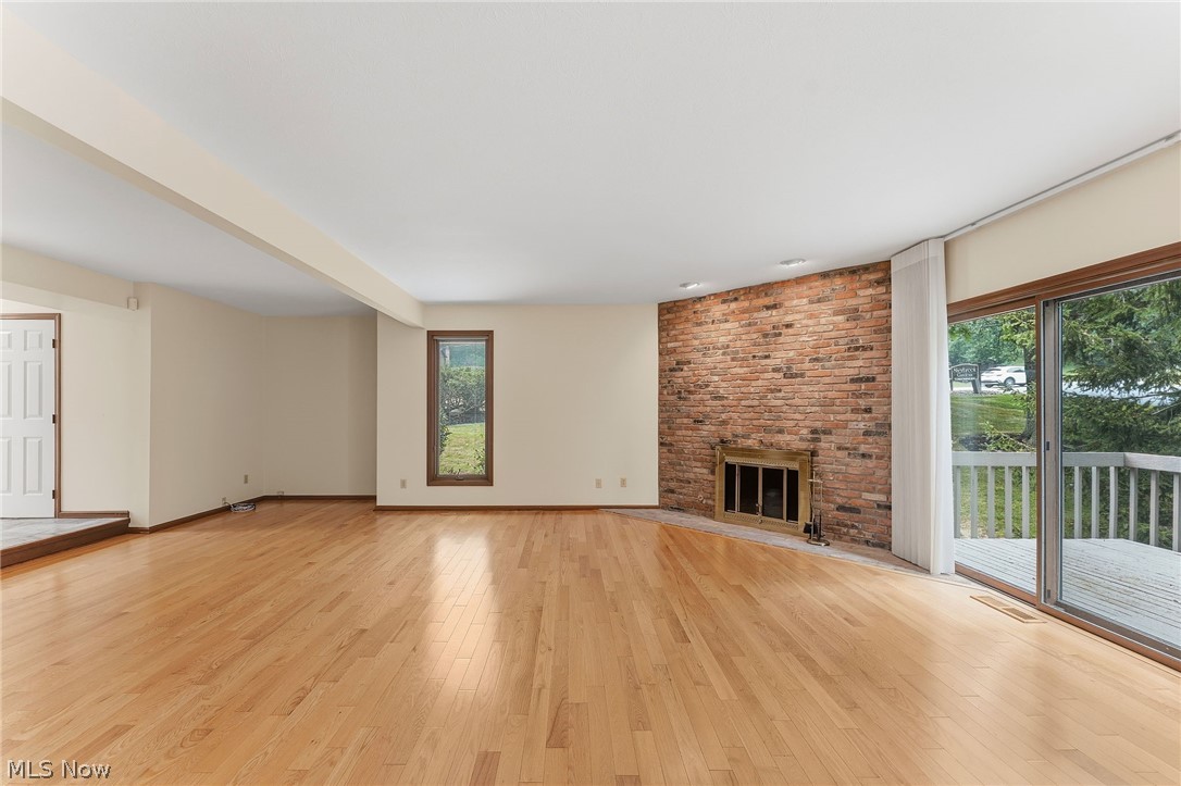 5741 Som Center Road, Unit 1 Solon, OH 44139 - Photo 11 of 50 Hardwood flooring throughout a spacious room featuring a brick fireplace with an ornate metal surround