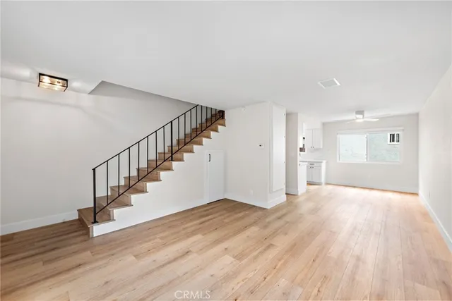 a view of an empty room with wooden floor and stairs