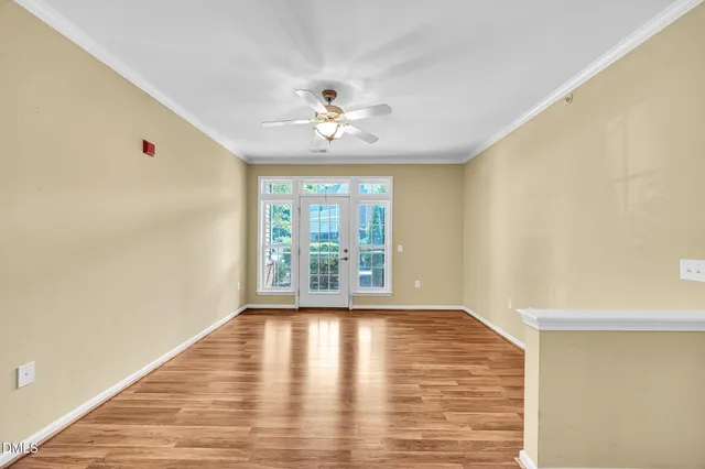 a view of an empty room with a window and wooden floor