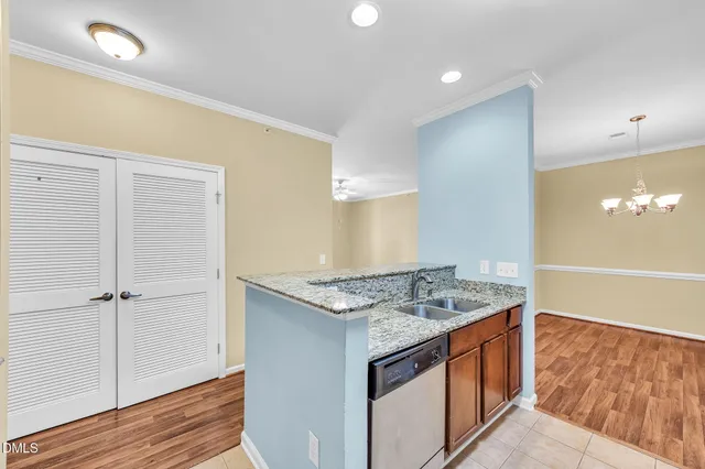 a view of kitchen island a sink wooden floor and a chandelier