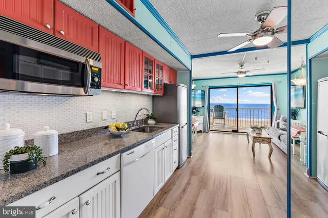 a kitchen with stainless steel appliances a stove top oven a sink a dining table and chairs with wooden floor