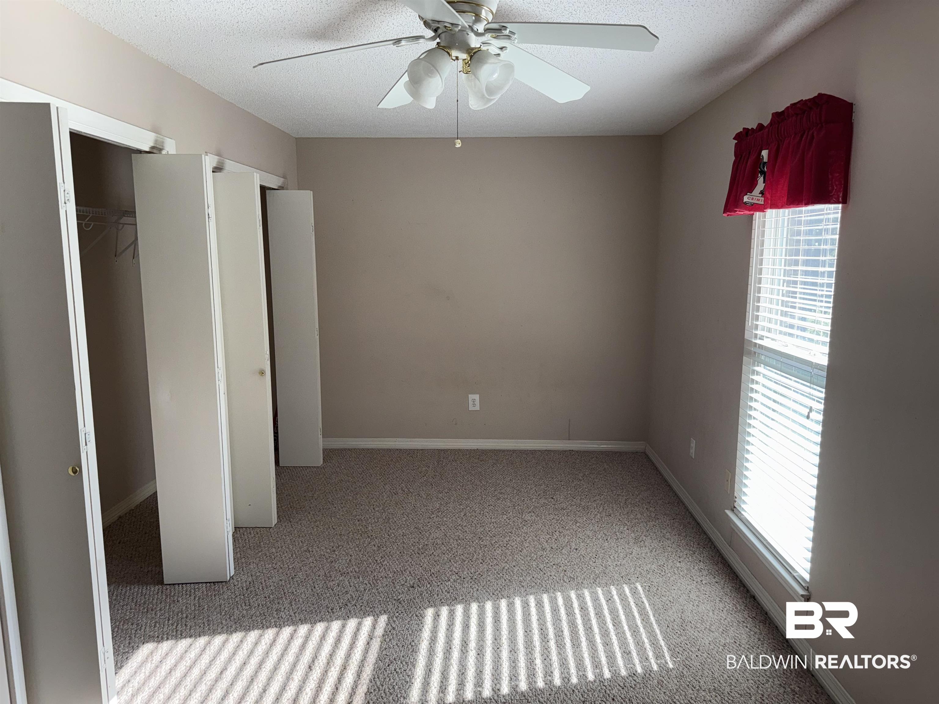103 Ann Street Daphne, AL 36527 - Photo 16 of 23 Unfurnished bedroom featuring light colored carpet, a textured ceiling, a closet, and a ceiling fan