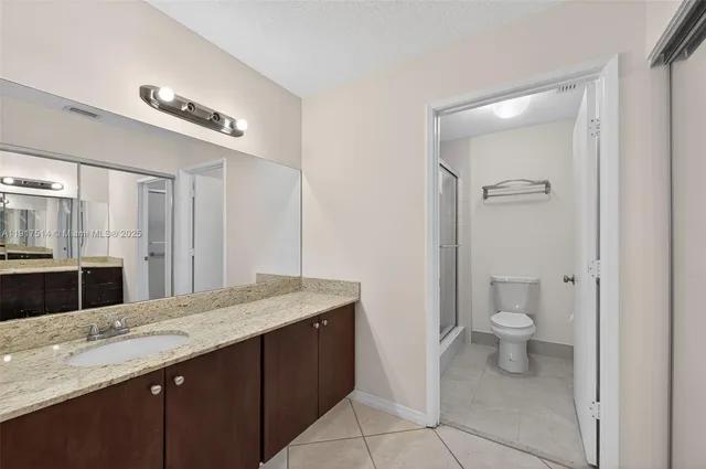 a bathroom with a granite countertop sink a toilet and a mirror