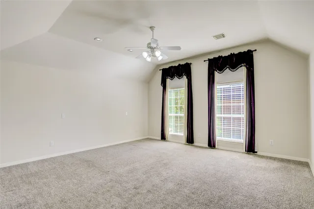 an empty room with windows and ceiling fan