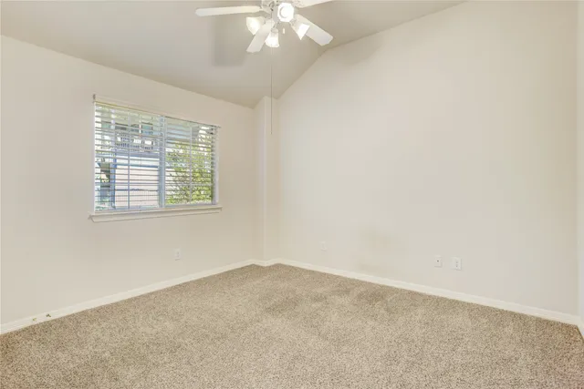 an empty room with a chandelier fan and windows