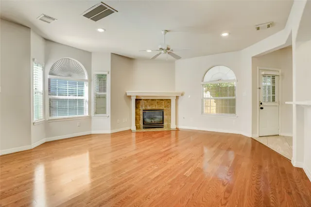 a view of an empty room with a window and wooden floor