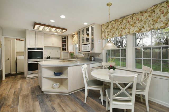 a kitchen with stainless steel appliances kitchen island granite countertop a table chairs and a refrigerator