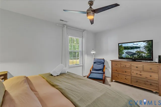 a bedroom with a bed a computer on desk and a dresser next to a window