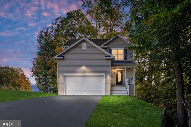 a front view of a house with a garden and trees