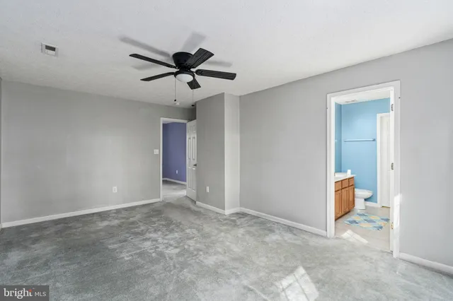 a view of an empty room and chandelier fan