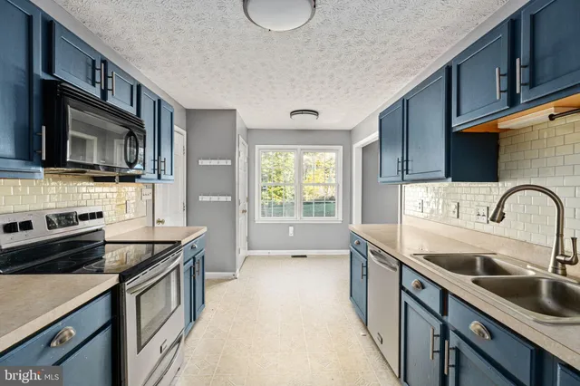 a kitchen with kitchen island granite countertop a sink stainless steel appliances and cabinets