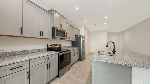 a kitchen with granite countertop white cabinets and stainless steel appliances
