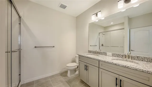 a bathroom with a granite countertop sink mirror vanity and toilet