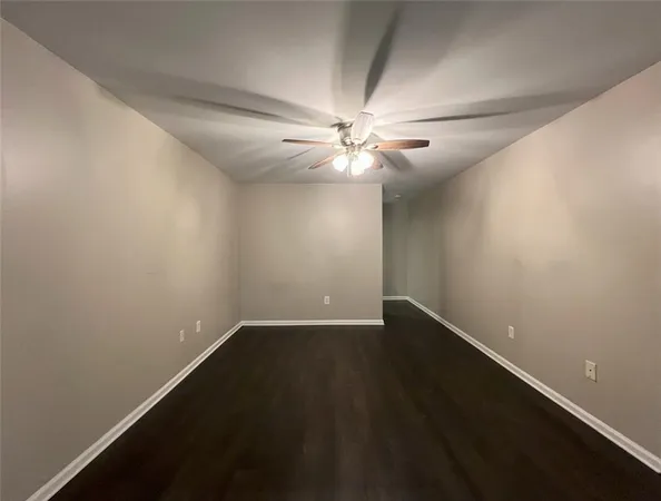 an empty room with wooden floor and fan