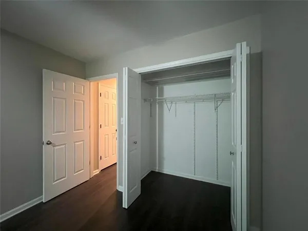 an empty room with wooden floor closet and windows