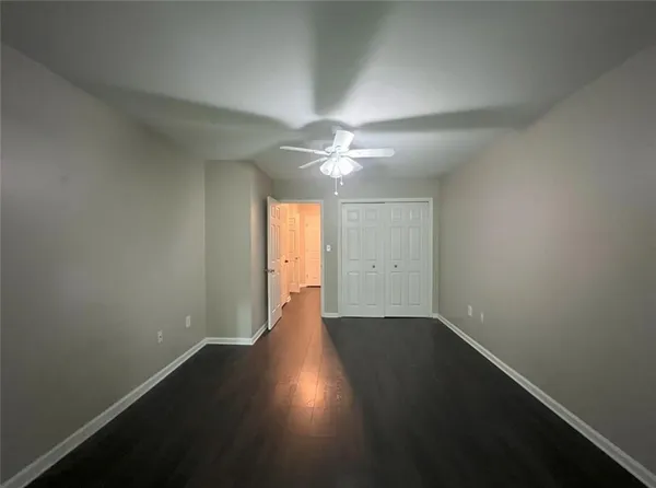 an empty room with wooden floor and fan