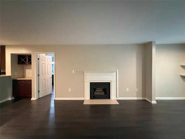 an empty room with wooden floor fireplace and windows