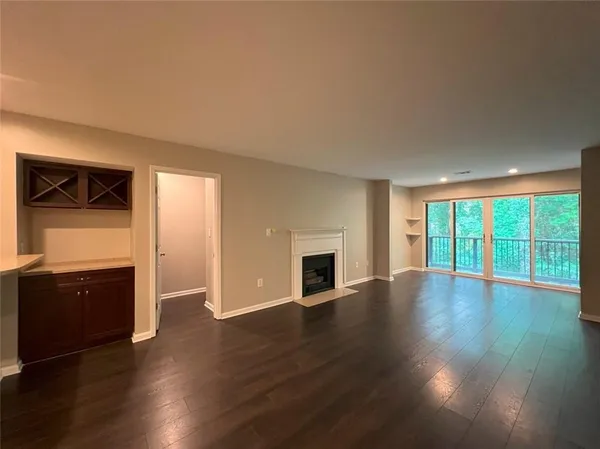 an empty room with wooden floor fireplace and windows