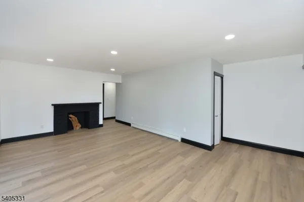 a view of an empty room with wooden floor and a fireplace