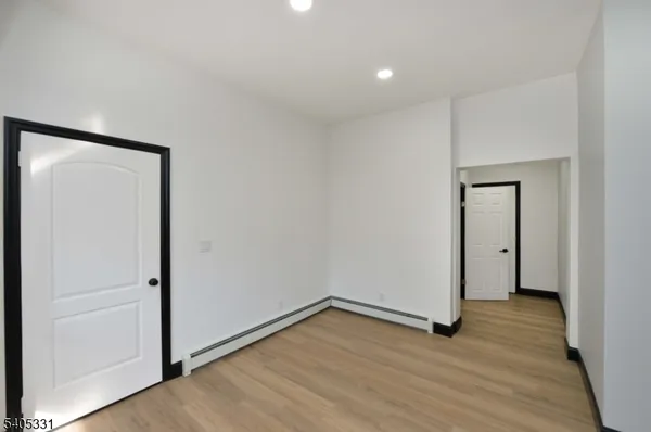 a view of an empty room with wooden floor and closet