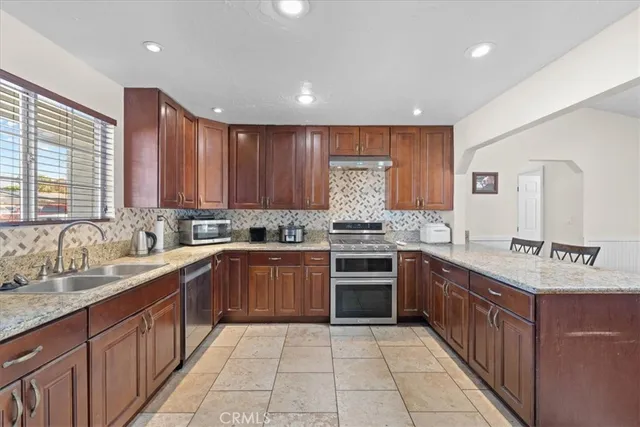 a large kitchen with stainless steel appliances granite countertop a sink counter space cabinets and a large window