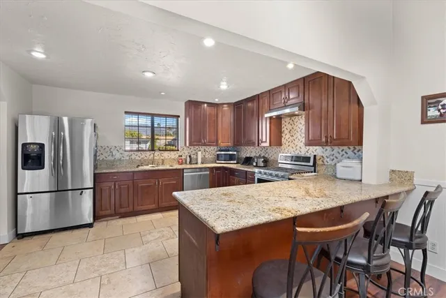 a kitchen with granite countertop a refrigerator a stove a sink dishwasher with a dining table and chairs