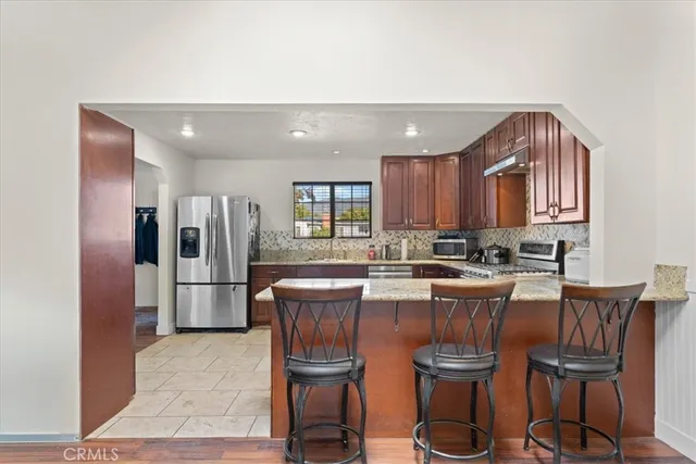 a large kitchen with sink a refrigerator and chairs