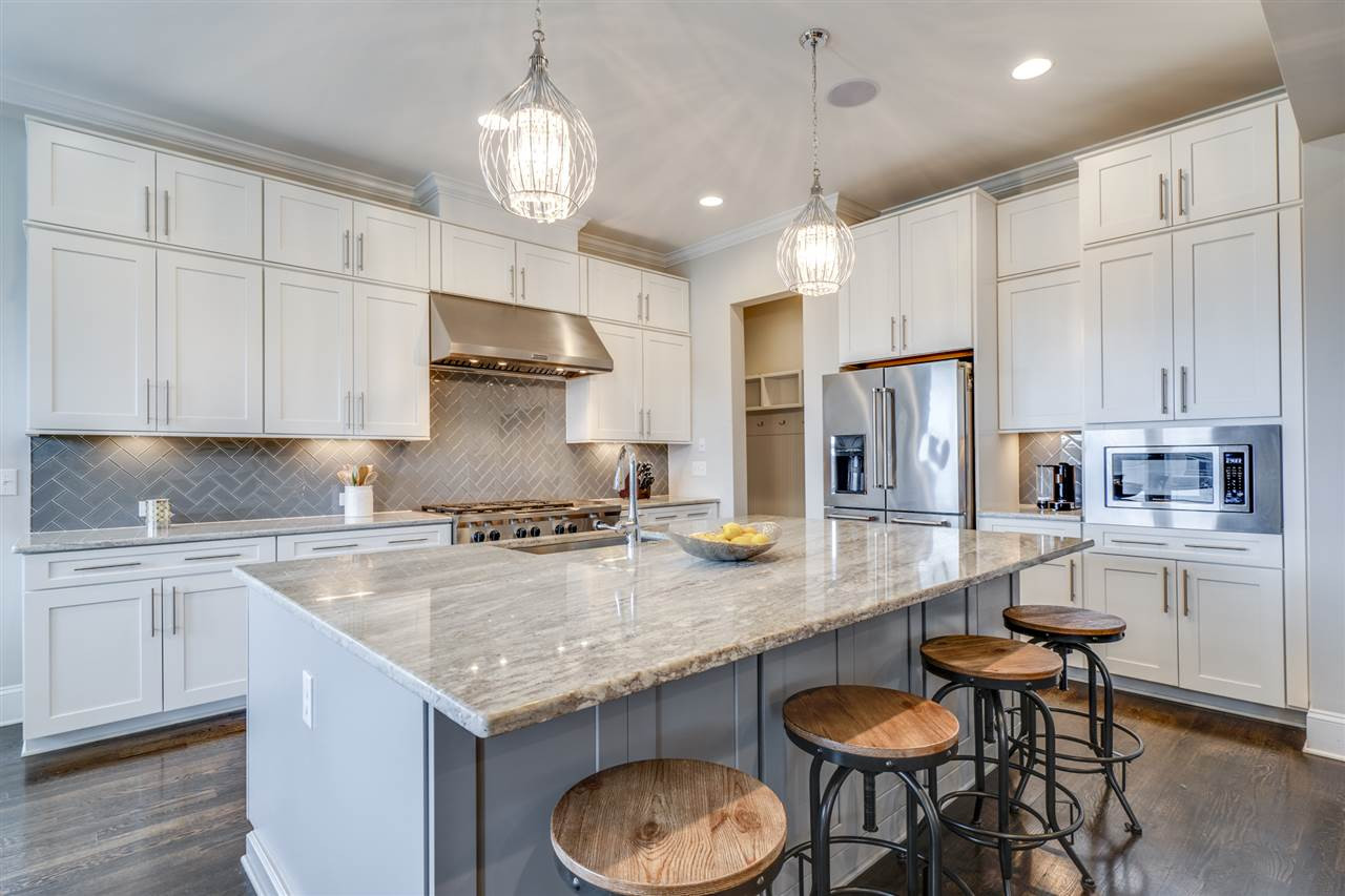 7504 Pinaster Place Raleigh, NC 27613 - Photo 8 of 30 This dream kitchen features cabinets to the ceiling, under cabinet lighting, Kitchen Aid 48" commercial style hood & stove w/ 6 burners + griller! Quartz countertops, an oversized island perfect for serving and more! Kitchen
