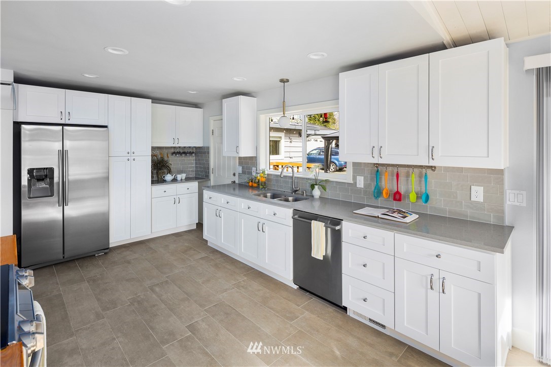 33 243rd Place Southeast Bothell, WA 98021 - Photo 10 of 28 a kitchen with granite countertop a white refrigerator oven a sink dishwasher and white cabinets with wooden floor