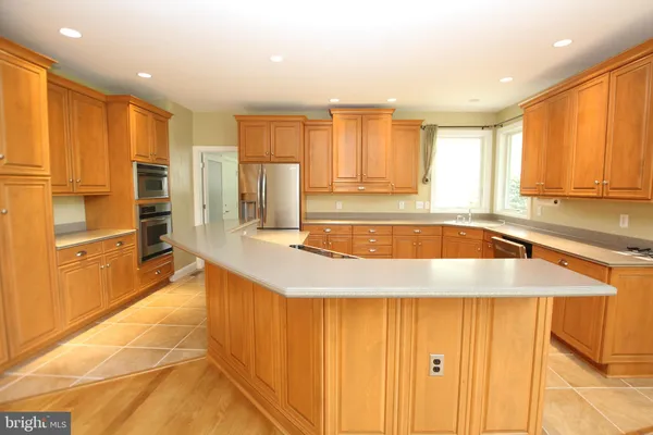 a kitchen with stainless steel appliances granite countertop a refrigerator a sink a stove with wooden cabinets and floor