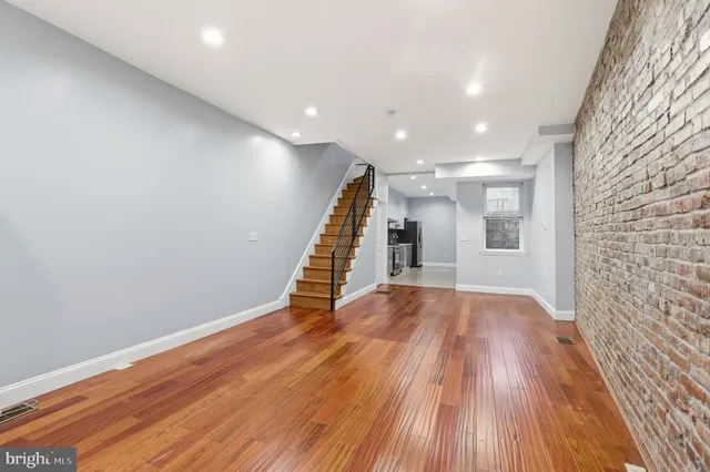 a view of an empty room with wooden floor and stairs