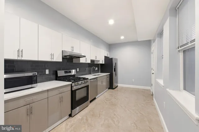a kitchen with granite countertop a sink a stove and refrigerator