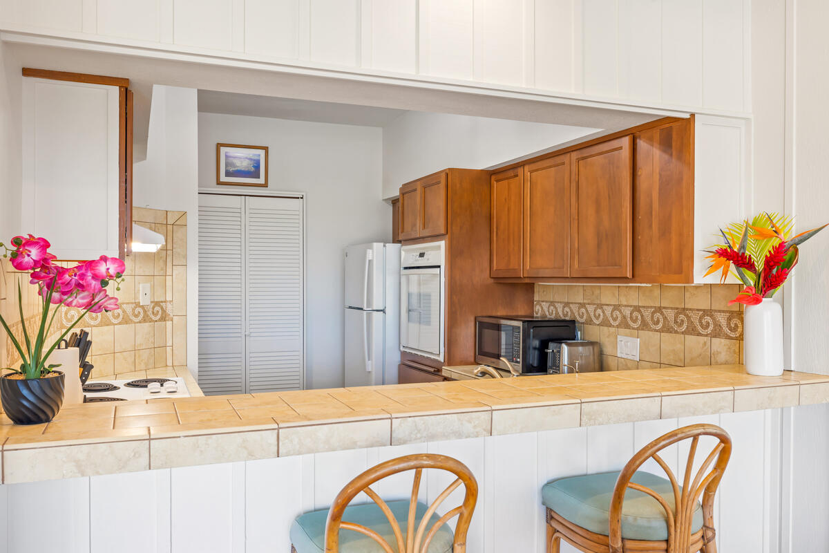 2371 Ho'ohu Road, Unit 703 Koloa, HI 96756 - Photo 11 of 27 a kitchen with stainless steel appliances granite countertop a refrigerator and a stove top oven